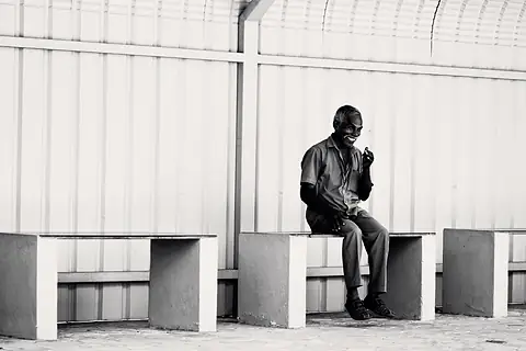 A man seated alone in a light corridor