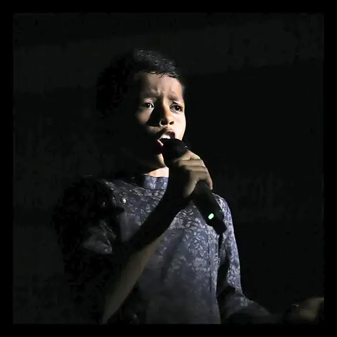 A singer holding a microphone on a dark stage