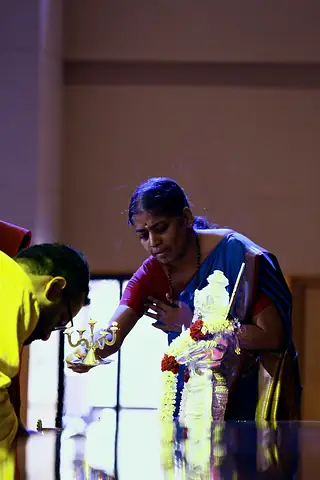 A teacher waving an aarti lamp before a garlanded murti
