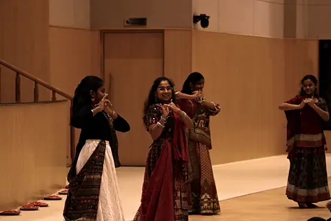 Girls in mirrored skirts dancing in the hall under warm light