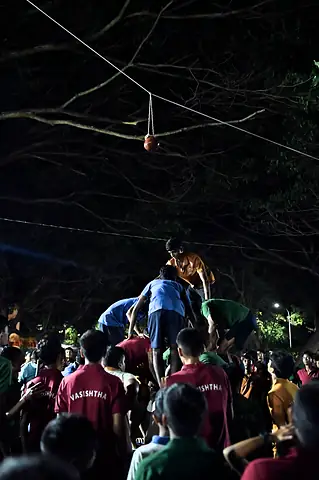 A human pyramid climbing towards a pot hung high in the dark