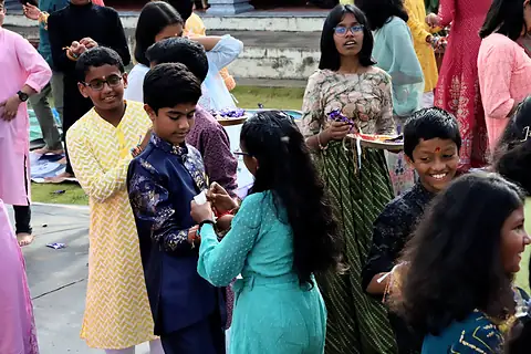 Students standing in pairs, some tying rakhis and some smiling at the camera