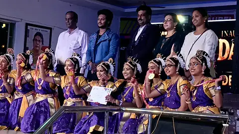 Girls in purple and orange dance costumes holding a certificate on a stage