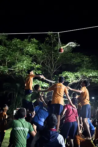Students forming a human pyramid at night beneath a hanging pot