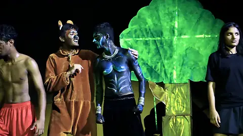 Actors in costume and body paint beside a glowing green tree