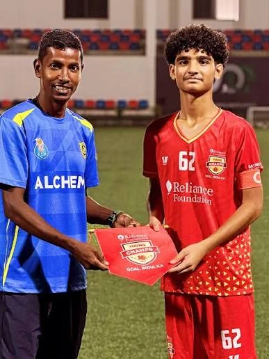 Divyaj DT, on the right in a red football kit, standing with another person.