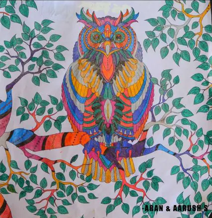 A patterned owl in rainbow colours on a branch among green leaves