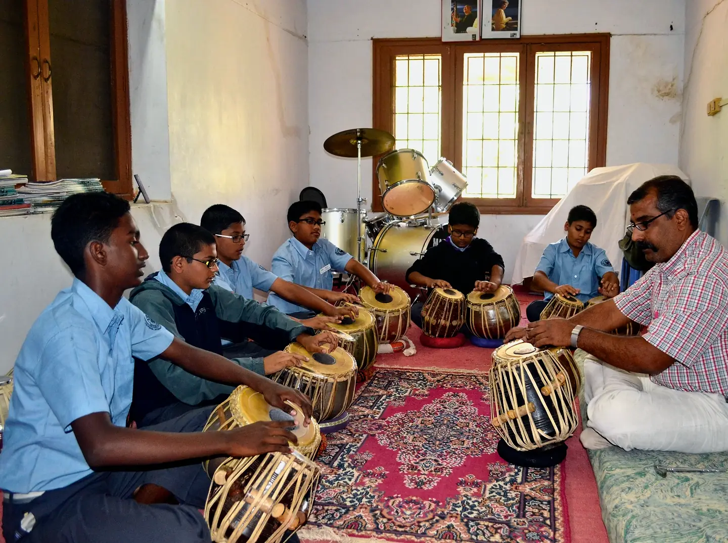 CIRS students seated on a carpet at tabla, their teacher beside them