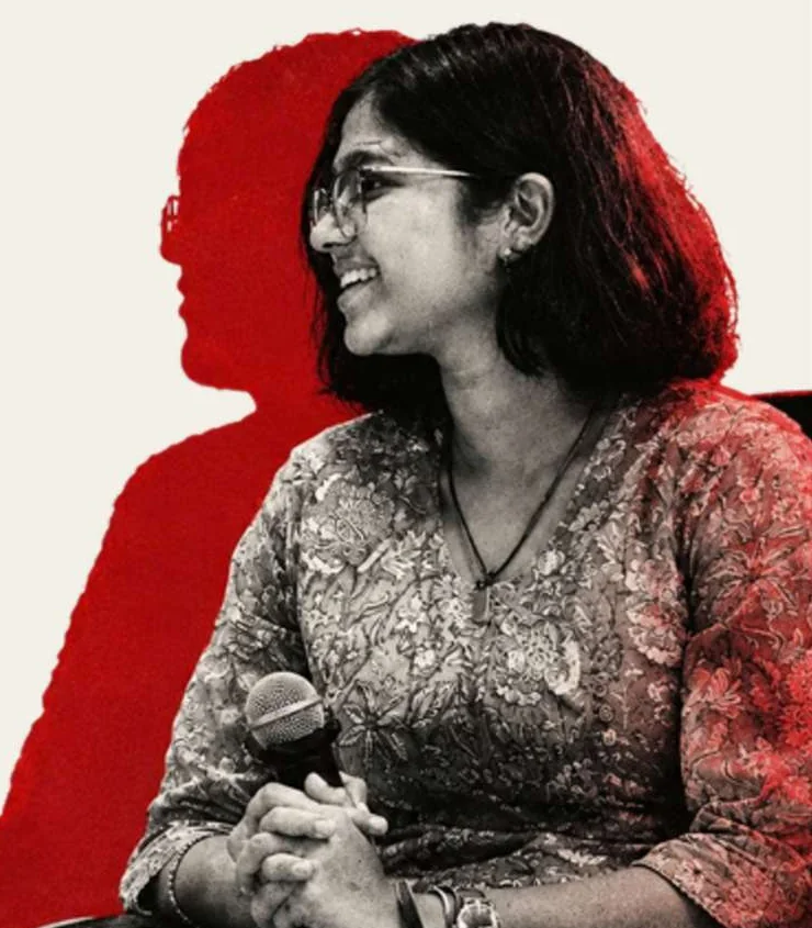 Rhea Sontakke, the editor, seated with a microphone in her hands, in black and white against a red cut-out shape