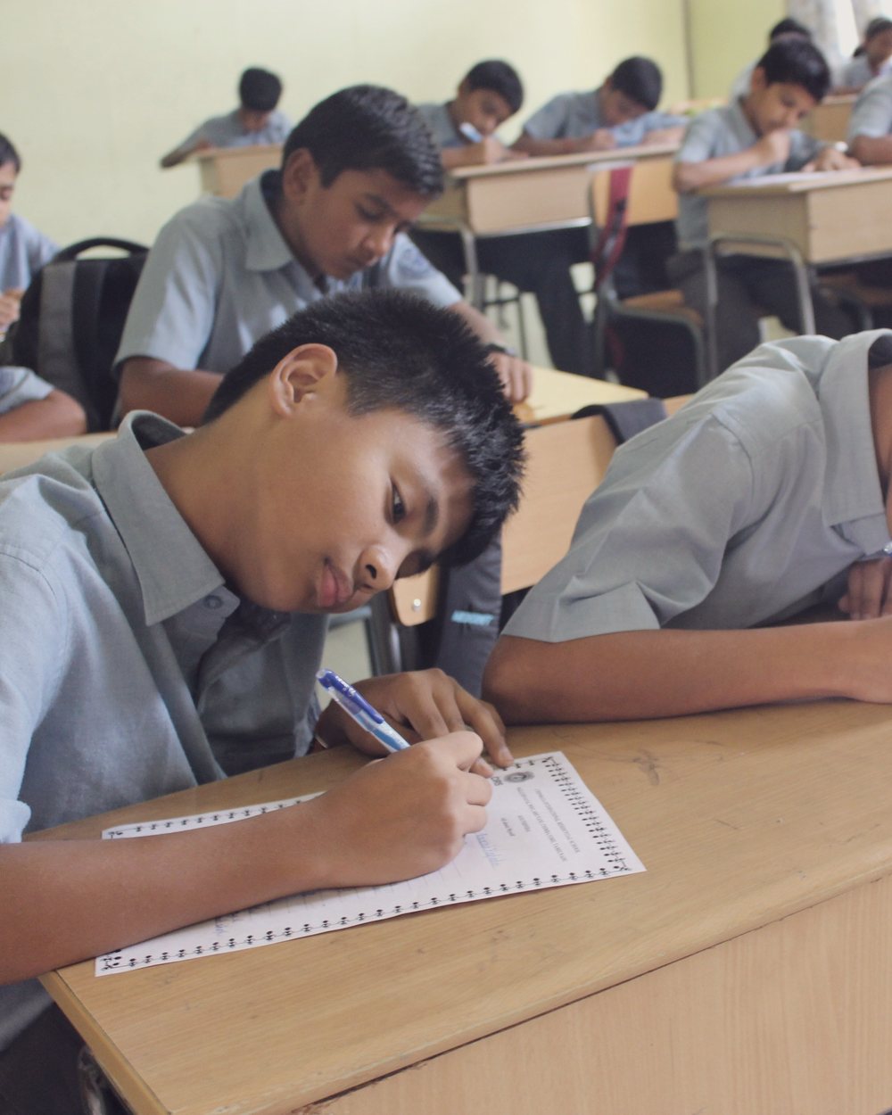 Students writing at rows of classroom desks