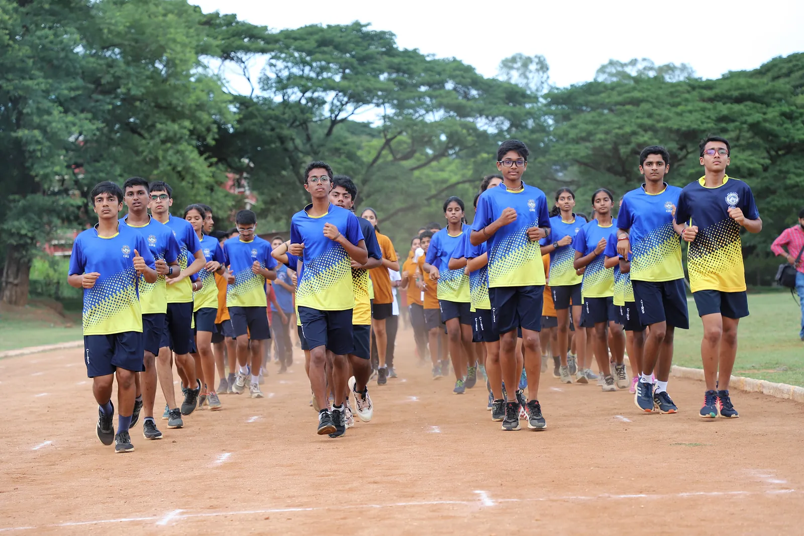 CIRS students running together across the athletic field, trees behind them