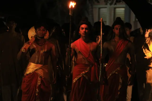 Students in costume walking in procession by the light of flaming torches