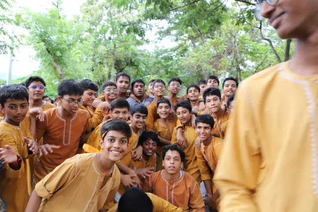 Boys in saffron kurtas gathered together, smiling at the camera