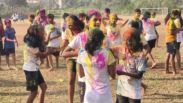 Students with colour on their faces and clothes crossing the playing field