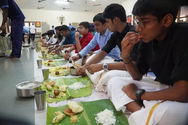A student in a white mundu eating rice from a banana leaf