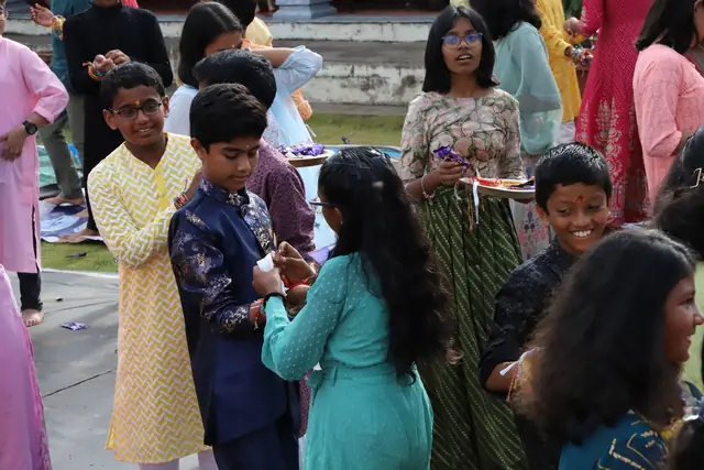 Students standing in pairs, some tying rakhis and some smiling at the camera