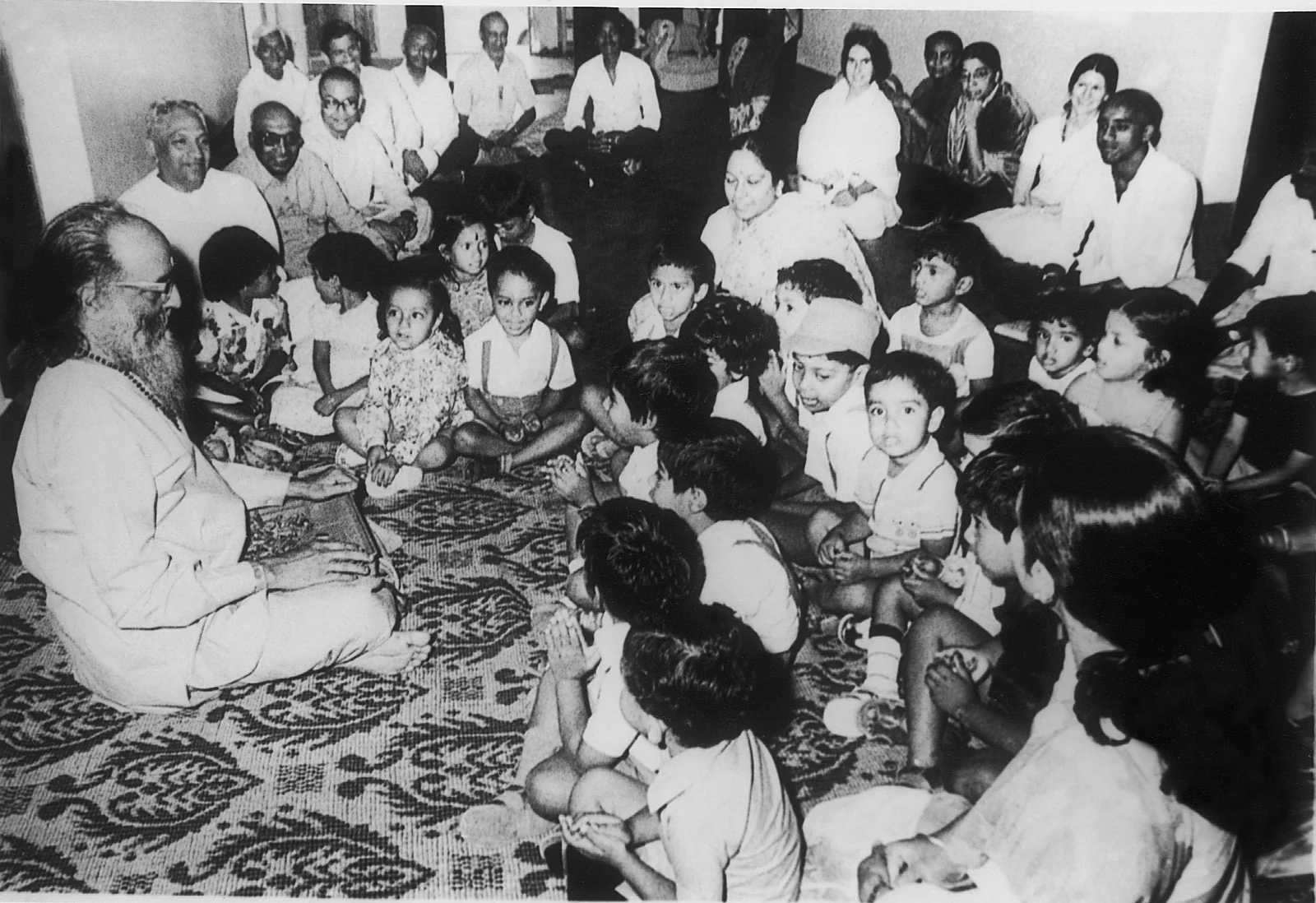 Swami Chinmayananda seated with a large circle of children and families