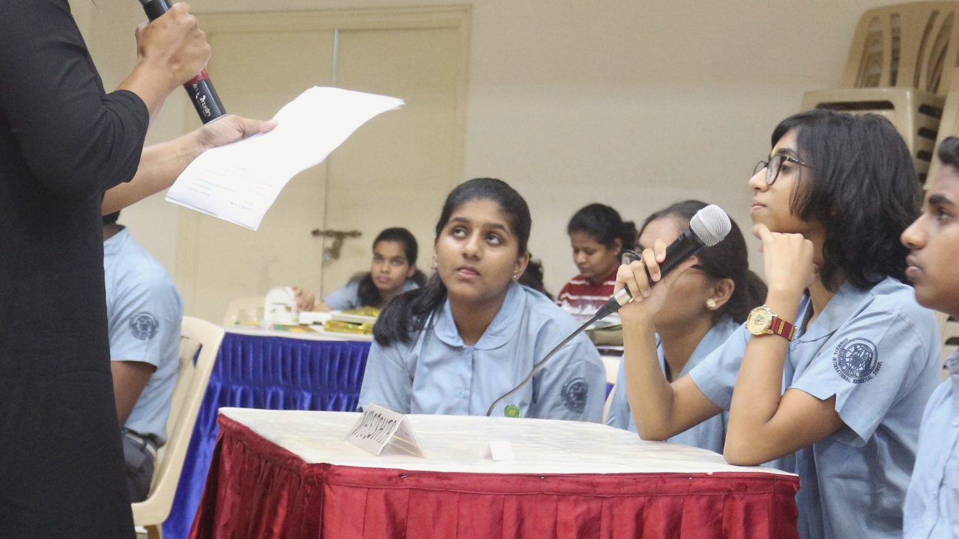 CIRS students discussing a quiz answer at a table, one student holding a microphone