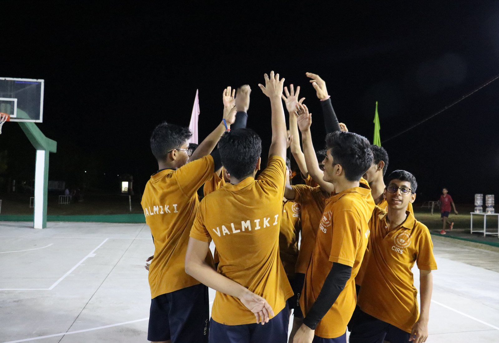 Valmiki players raising their hands together in named yellow shirts