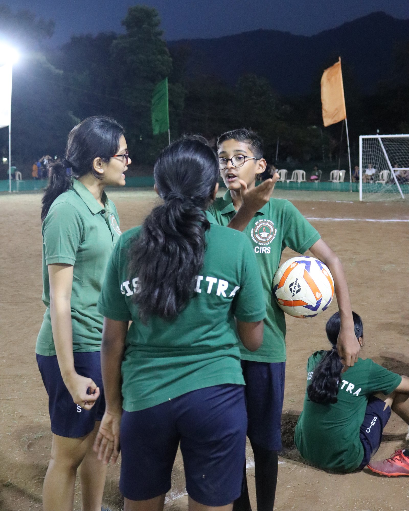 Vishwamitra students talking beside the court, with house lettering visible on green shirts