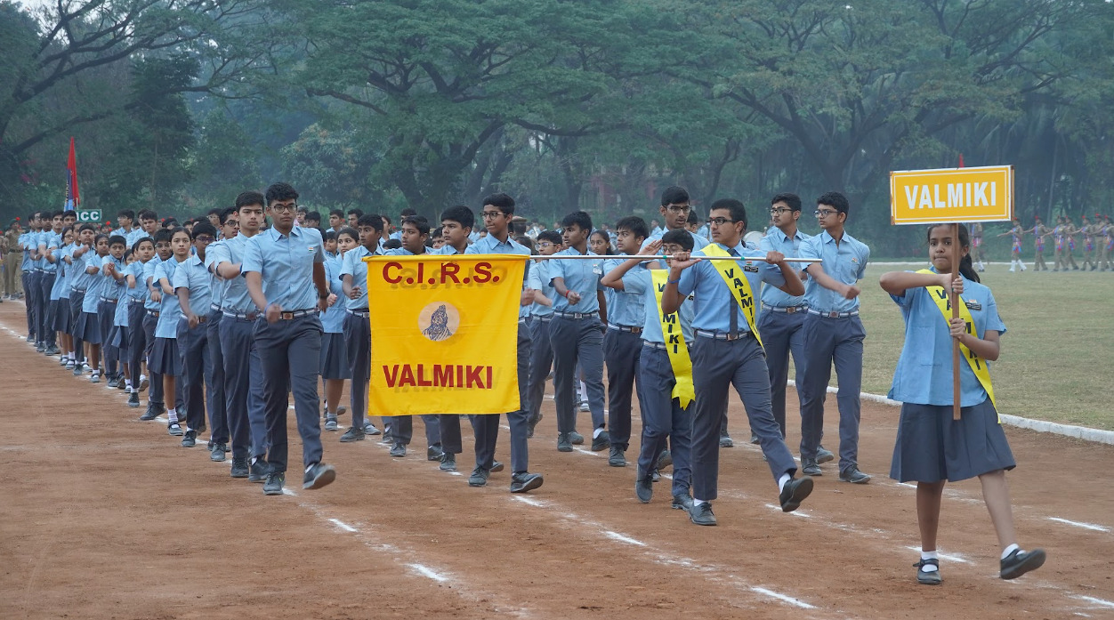 Valmiki students marching behind their named house banner