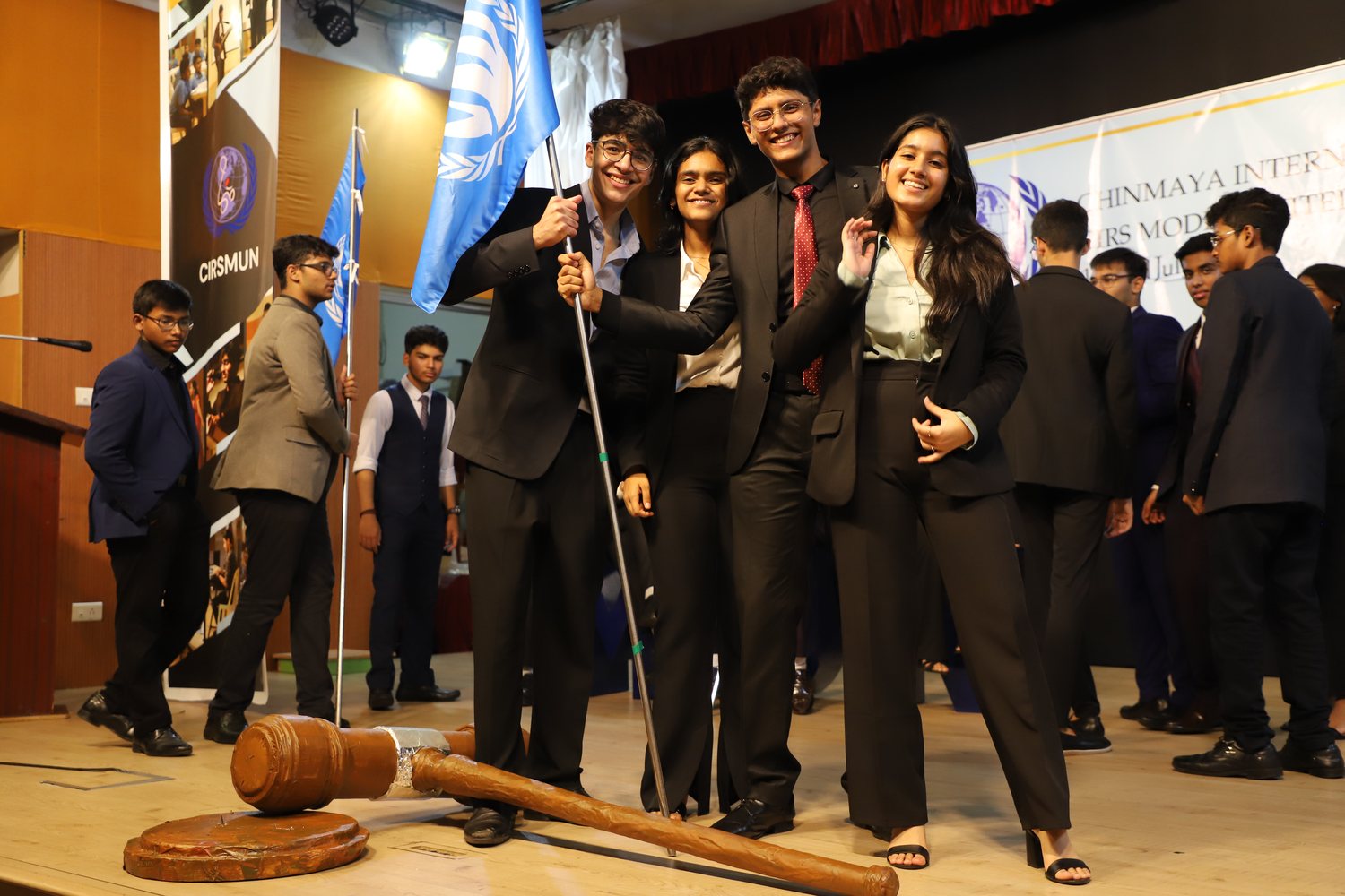 Students in suits gathered with a flag at a CIRS Model United Nations