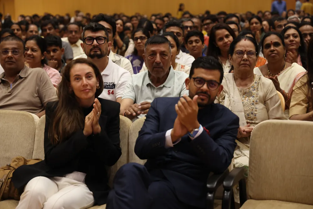 Two members of the audience in the front rows, a woman and a man, applauding, with other people seated behind them
