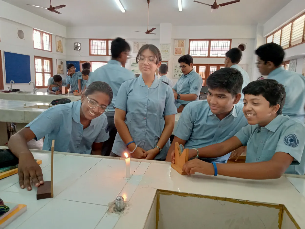 Grade 10 students watching a candle's reflection in a mirrors experiment