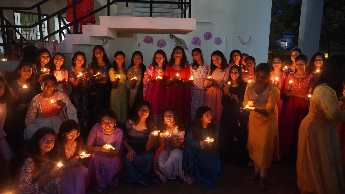 Students holding lit diyas on Diwali evening