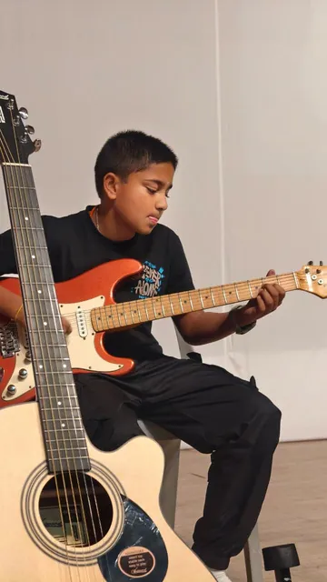 A student playing guitar at the Inter-House Solo Instrumental Competition