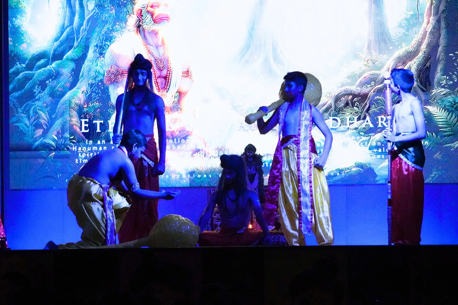 Students in costume on a blue-lit stage during a skit