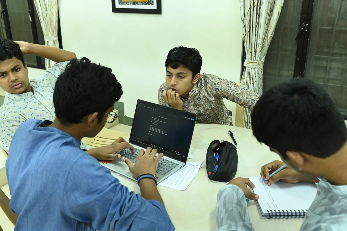 Students at a table with a laptop and a notebook