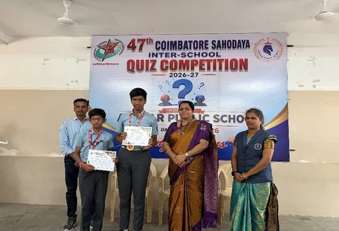 Students and adults with certificates before a Coimbatore Sahodaya Inter-School Quiz Competition banner
