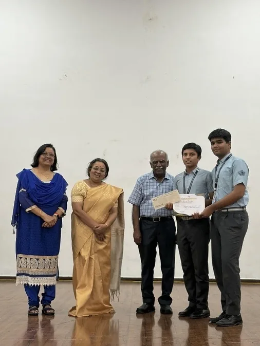 Two women, two men and a student holding a certificate in a room