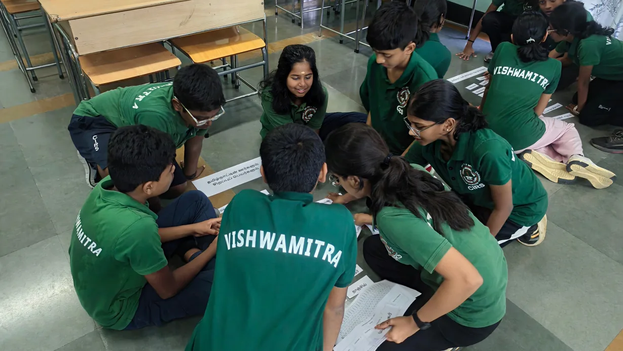 Students in green house shirts gathered around a desk