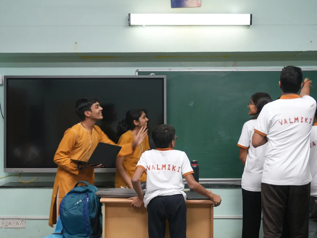 Students in house shirts standing at a green board