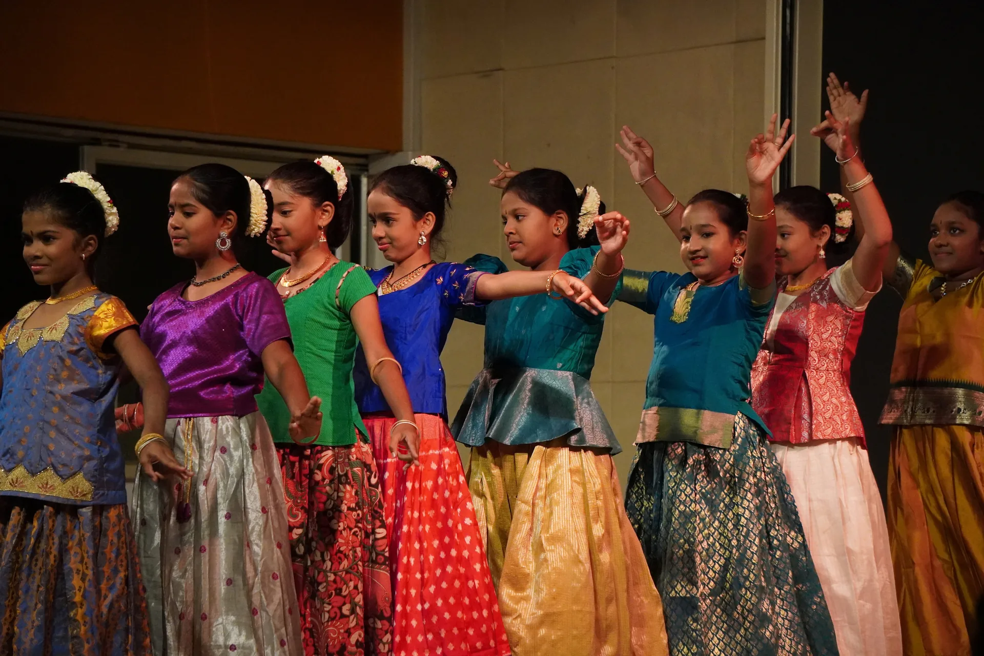 Girls in bright traditional skirts dancing in a row on a stage
