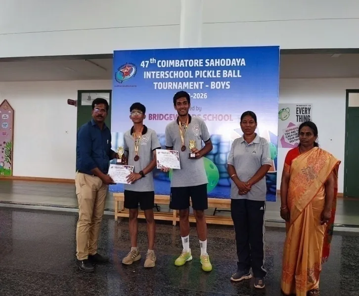 Boys holding trophies and certificates before a Coimbatore Sahodaya pickleball tournament banner
