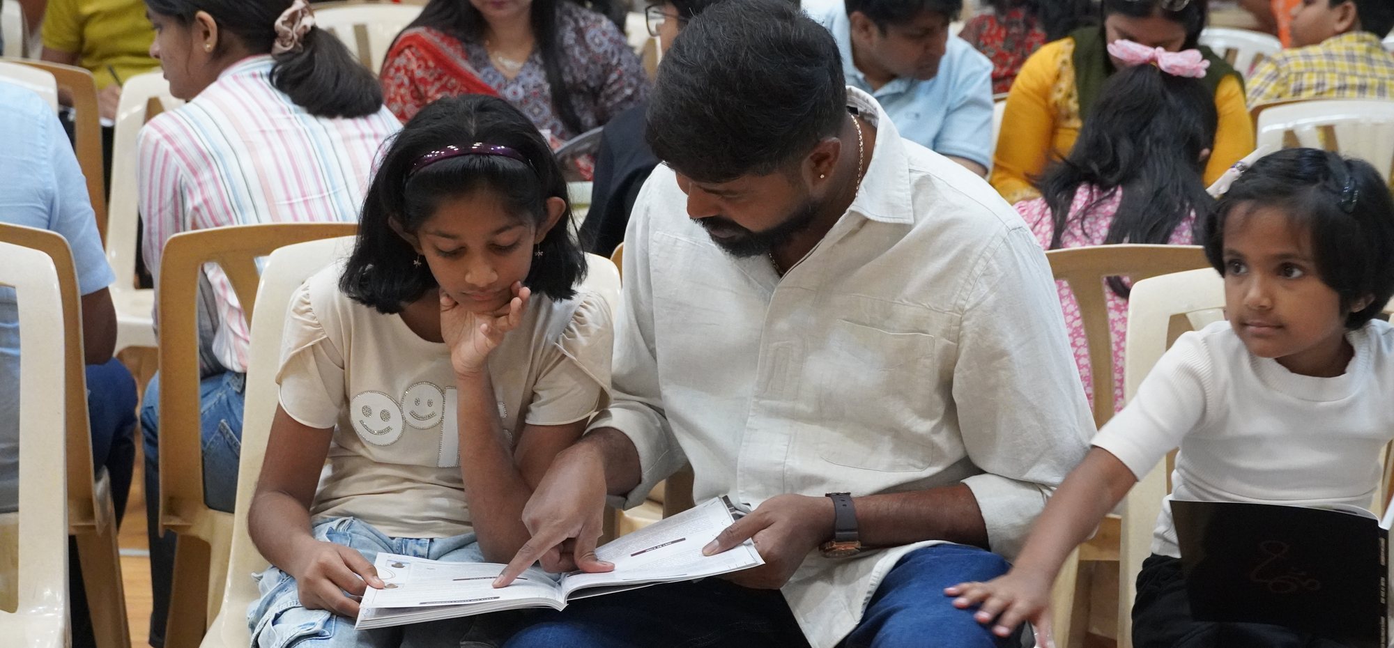An adult helps a child read a booklet during CIRS new student and parent orientation