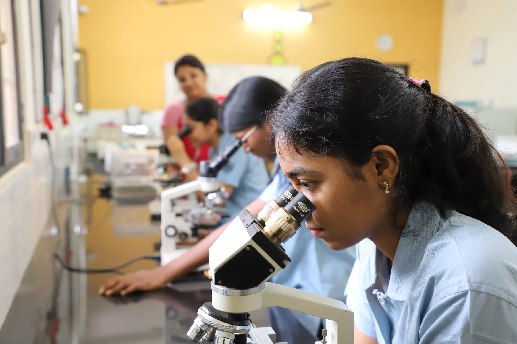 A CIRS student looking into a microscope in a biology laboratory