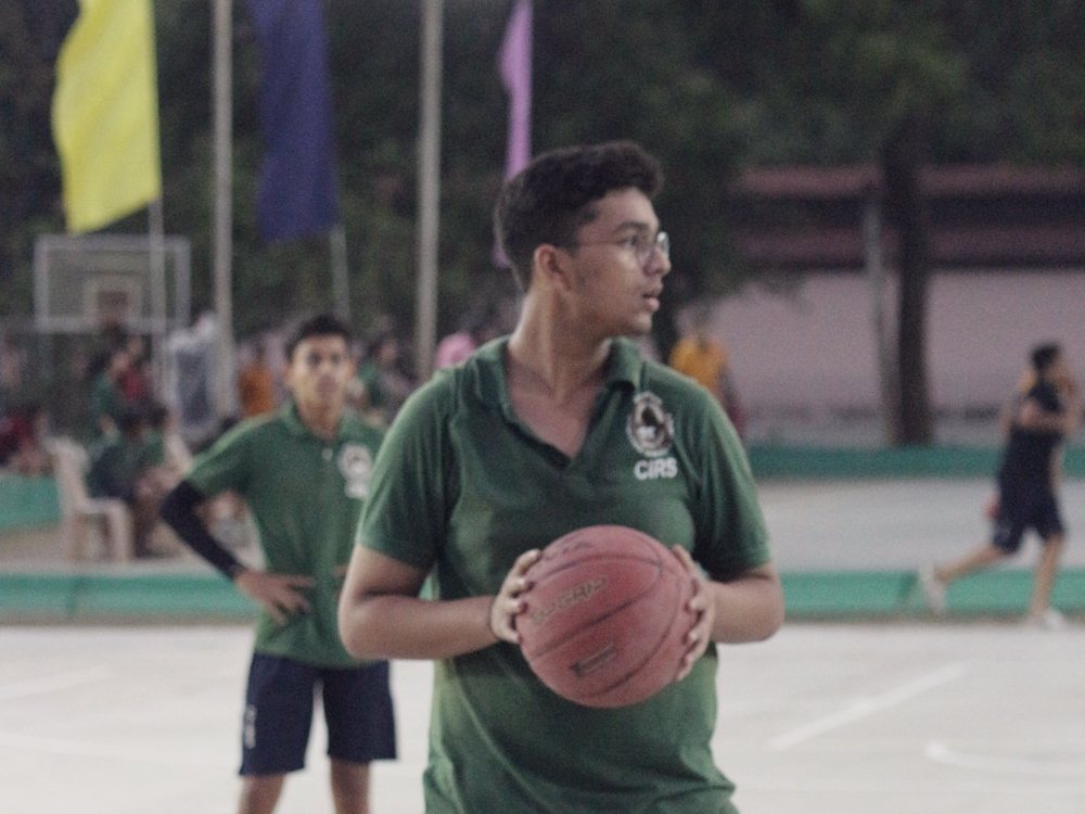 A player holding the ball at the top of the key as the court lights come on