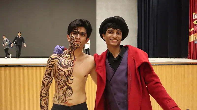 Two actors after the show, one in swirling body paint, one in a red coat and top hat