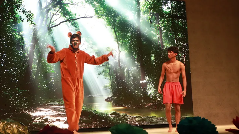 The actor in the bear costume and a boy in a forest clearing lit by shafts of light