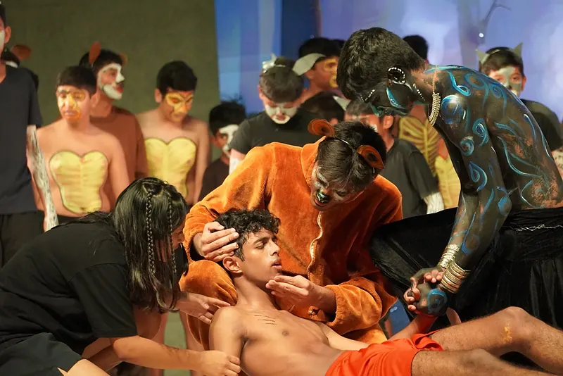 The cast gathered around a boy lying on the stage